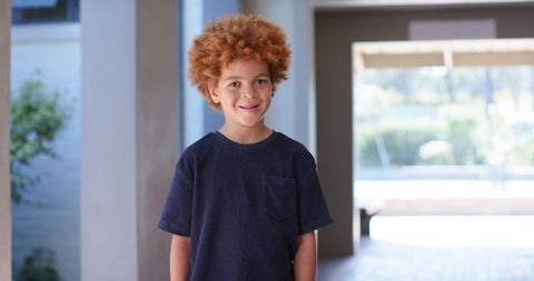 African american boy standing in sunlit patio courtyard wearing navy t-shirt