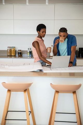 Couple collaborating on blueprints in modern kitchen interior