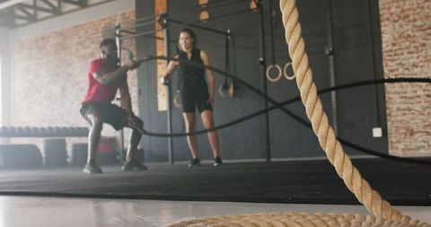 Trainer Guiding Client with Battle Ropes