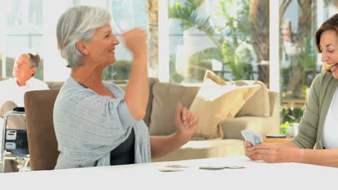 Seniors Enjoying Card Game in Care Facility Common Area