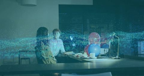 Colleagues collaborating at desk with holographic data stream, balloons and laptop for planning