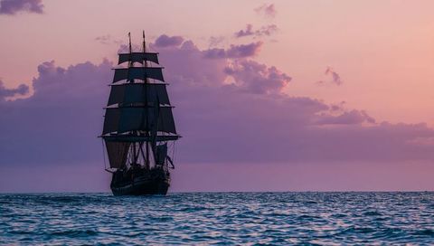 Majestic three-masted sailing ship at sea during vibrant sunset