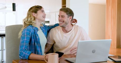 Smiling Couple Using Laptop and Smartphone at Home