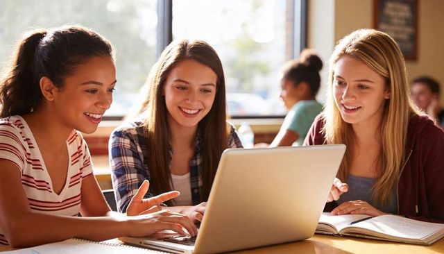 Three Teens Collaborating in Sunlit Campus Library Preparing for Exam Using Laptop