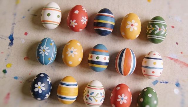 Hand-painted Easter Eggs Flatlay Featuring Daisies, Stripes and Paint Splatters on Craft Table