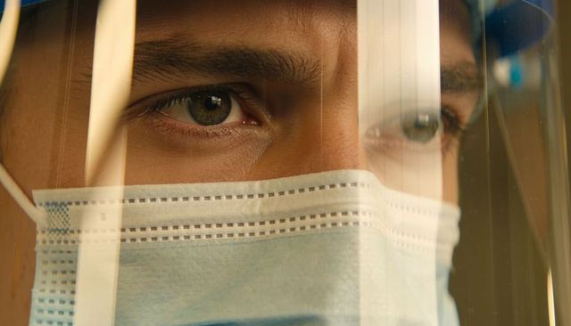 Healthcare worker wearing surgical mask and face shield closeup with reflective visor
