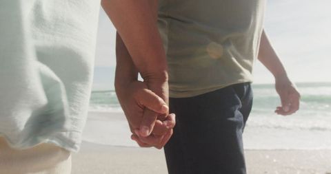 Senior Couple Holding Hands While Walking on Tranquil Beach