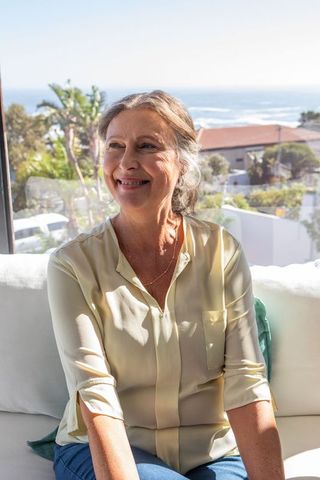 Content senior woman enjoying coastal view from balcony sofa