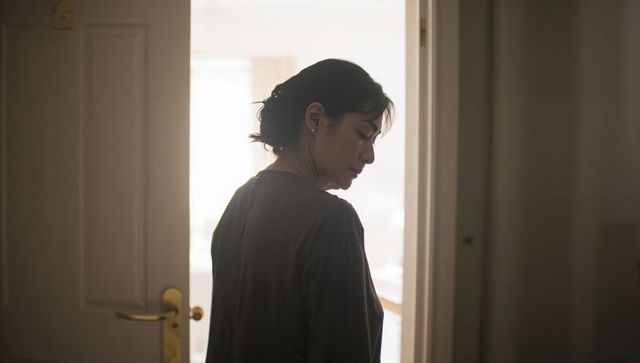 Backlit woman standing in doorway gazing into bright room contemplative interior moment
