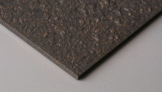 Dark granular panel close-up showing layered edge and textured speckled surface material
