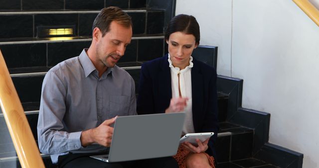 Coworkers Collaborating on Staircase Using Laptop and Tablet in Office - Download Free Stock Images Pikwizard.com