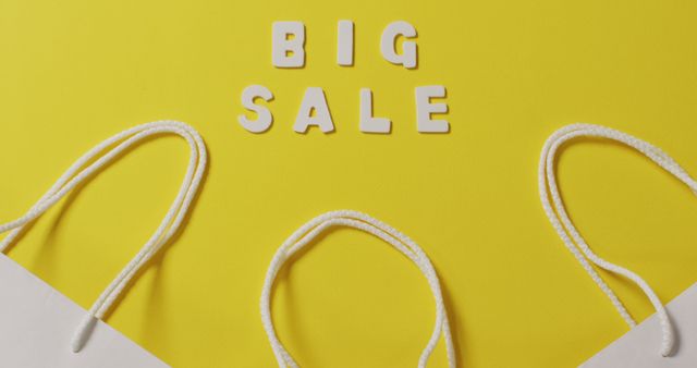 Big sale text in white and gift bags with string handles on yellow background. Shopping, sale and retail concept digitally generated image.