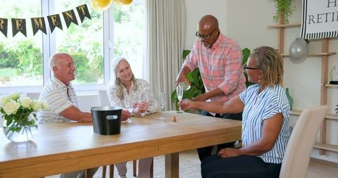 Senior friends enjoying wine celebration gathering at home