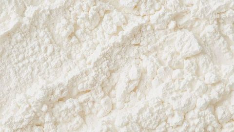 Granular white milk powder texture on flat surface