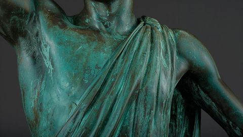 Displaying verdigris bronze torso draped in toga with corrosion patina close-up detail