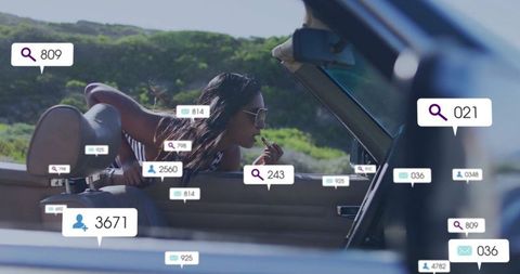 Woman applying lipstick in convertible with social notifications