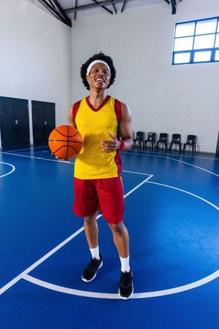 African american man holding basketball on court smiling confidently