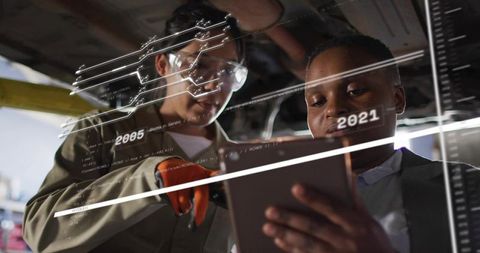 Diverse female technicians using tablet with augmented reality diagnostics under vehicle