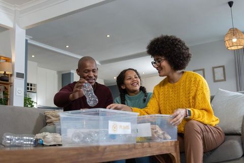 Diverse family sorting recyclables at home practicing sustainable habits together