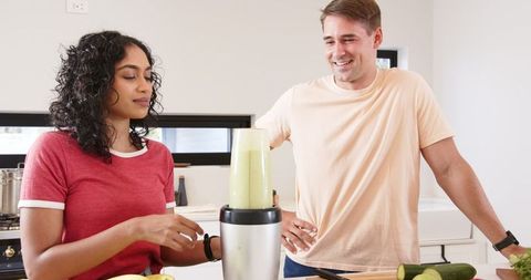 Diverse Couple Preparing Green Smoothie Together in Modern Kitchen