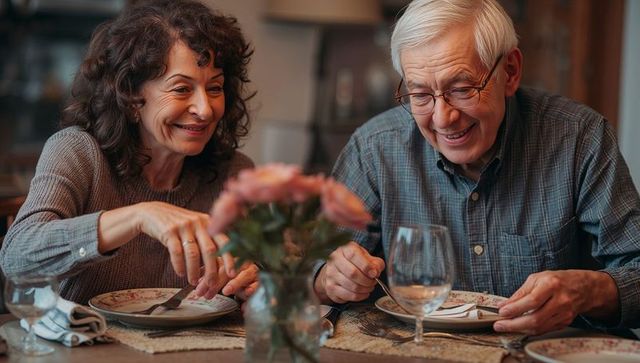 Smiling senior couple sharing cozy home dinner with floral table setting and warm lighting