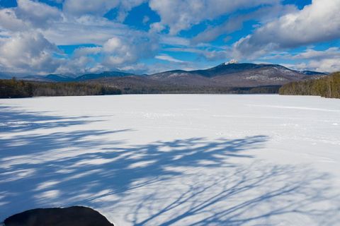 Frozen lake stretching toward snowcapped mountains under dramatic winter sky
