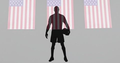 Silhouette basketball player in front of us flags