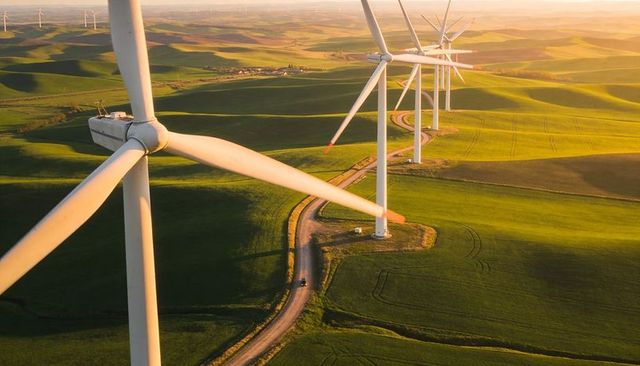 Sunlit Wind Turbine Line Crossing Rolling Farmland at Golden Hour Aerial View