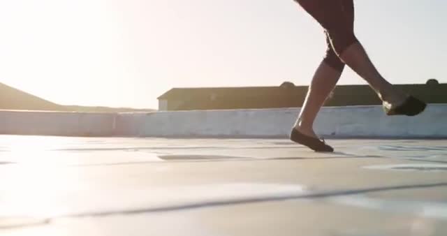 Depicting grace and dedication, this scene captures a male ballet dancer practicing on a rooftop at sunrise, emphasizing the beauty of movement. Perfect for projects highlighting passion in the arts, motivation, serene moments, or outdoor activities. Useful for dance class promotions or inspirational content focusing on the youthful discipline and morning routines.