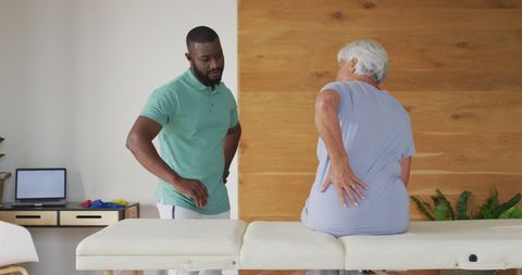 Physiotherapist assisting senior with back pain