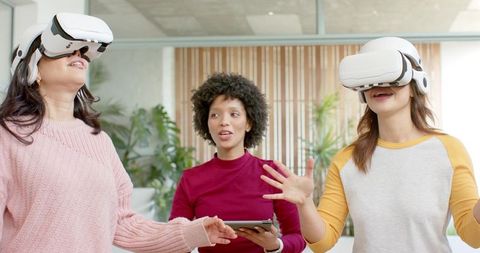 Multiracial Women Testing Virtual Reality Headsets During Collaborative Office Workshop