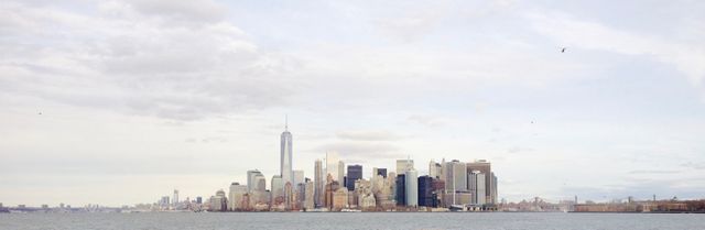 Panoramic view of a city skyline with towering skyscrapers and modern high rises near the waterfront. Ideal for use in travel brochures, blogs about urban planning and architecture, backgrounds for city-related presentations, and websites highlighting city attractions.