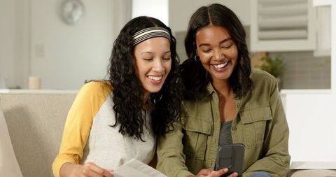 Mother and daughter smiling at smartphone together