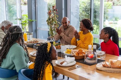 Multigenerational african american family sharing festive thanksgiving dinner and gratitude