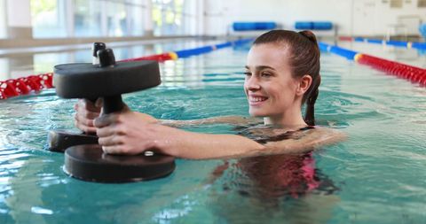 Woman engaging in aqua aerobics with dumbbells in pool