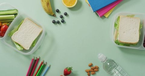 Healthy Lunchboxes with Vegan Snacks and School Supplies on Pastel Background