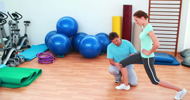 Physical therapist assisting woman with an exercise in rehabilitation center. Medical professional demonstrating correct form during a stretching session. Can be used for advertising physiotherapy services, health and wellness campaigns, fitness guides, and recovery program materials.