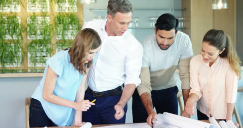 Colleagues Collaborating on Blueprint in Modern Office Setting