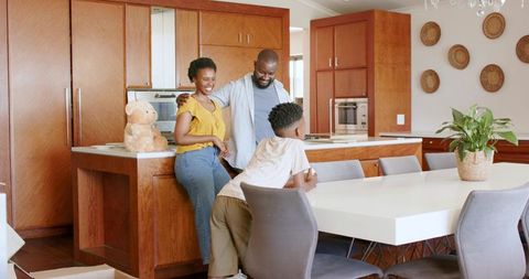 African American family enjoying morning in modern sunlit kitchen with wooden island