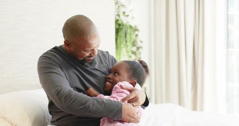 Affectionate Father-Daughter Hug in Cozy Bedroom Setting