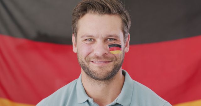 Confident man with German flag face paint smiling in front of German flag - Download Free Stock Images Pikwizard.com