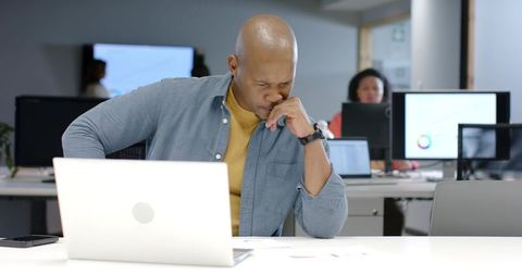 African American man concentrating over laptop and documents in modern open office