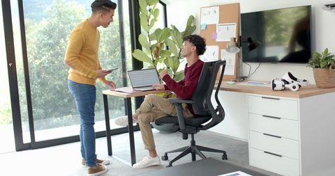 Young coworkers collaborating in bright home office with laptop smartphone and modern decor