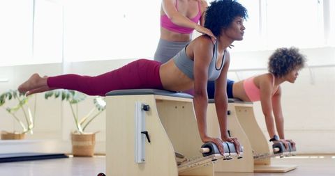 Women Practicing Pilates in Modern Fitness Studio with Instructor