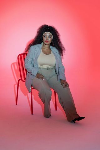 Confident mid-adult african american woman sitting on red chair wearing gray blazer