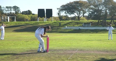 Teenage girl adjusting stumps on cricket field outdoor matches