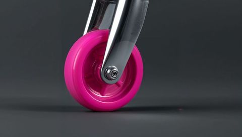 Magenta caster wheel and polished chrome fork closeup showing axle bolt and reflection