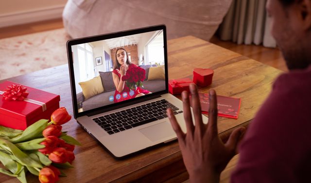Young woman blowing kiss to boyfriend during virtual date on laptop. Suitable for online dating, long-distance relationships, Valentine's Day celebrations, and promotional use in technology or romantic contexts.