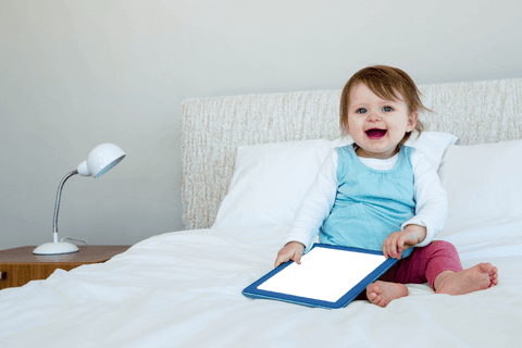 Cute Baby Holding Tablet on Bed with Transparent Smile - Download Free Stock Videos Pikwizard.com