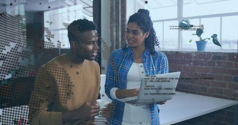 Developers Discussing Code On Laptop In Brick Office With Coffee